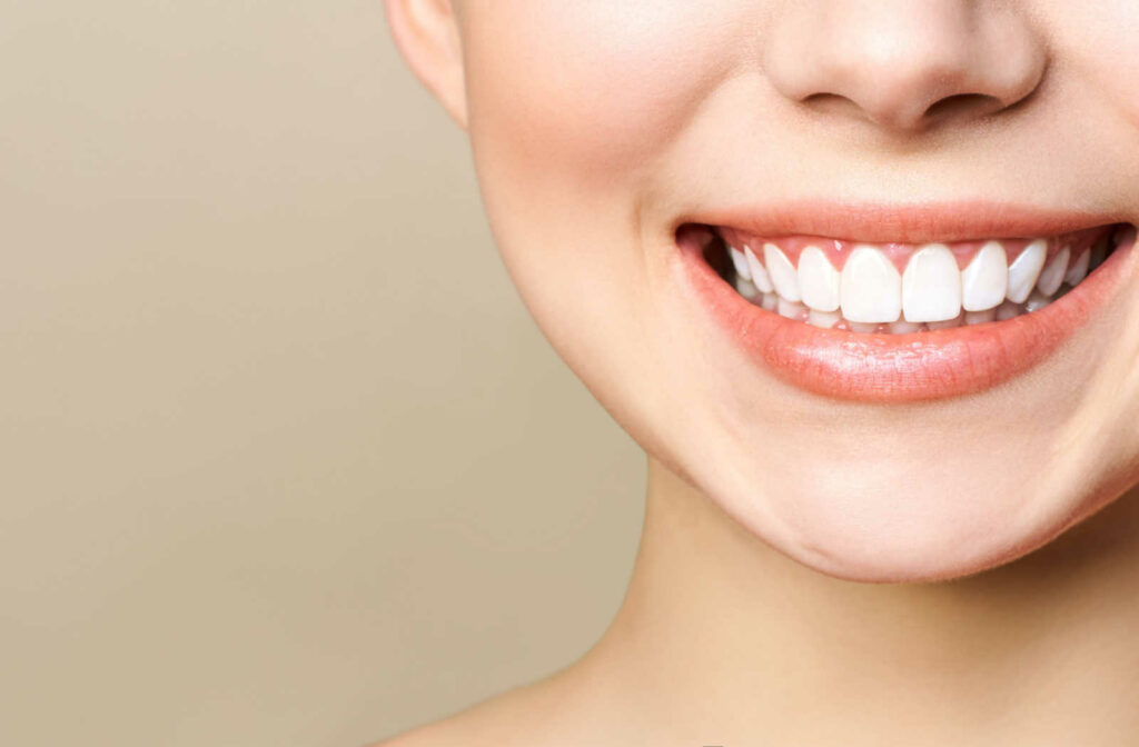 A close-up of a young woman with perfectly healthy teeth smiles after getting a whitening treatment from a cosmetic dentist.