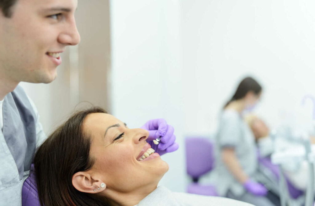 A male doctor and his female patient  is choosing the colour for her new veneers.