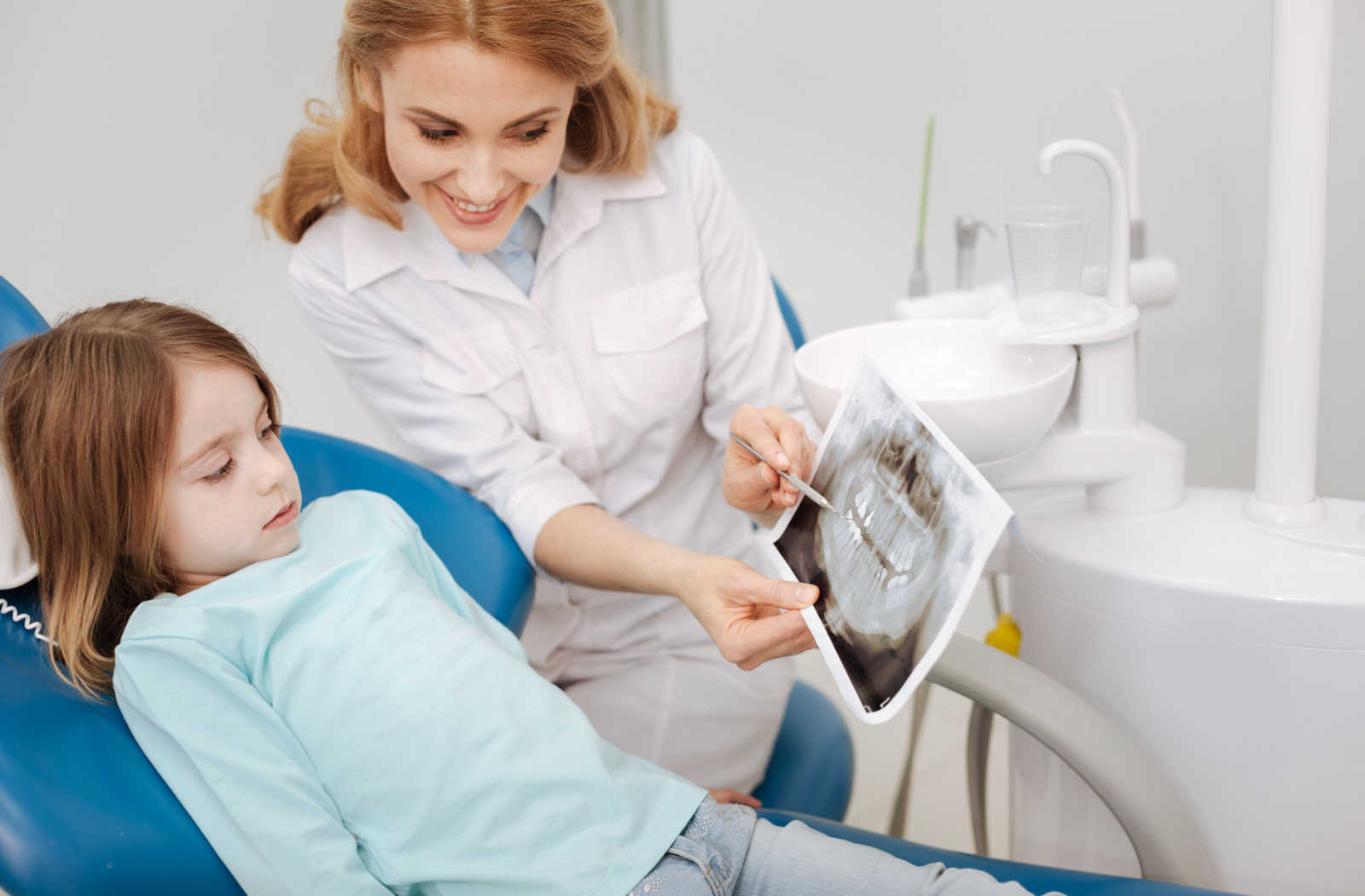 A young girl is shown her x-ray results by the dentist.