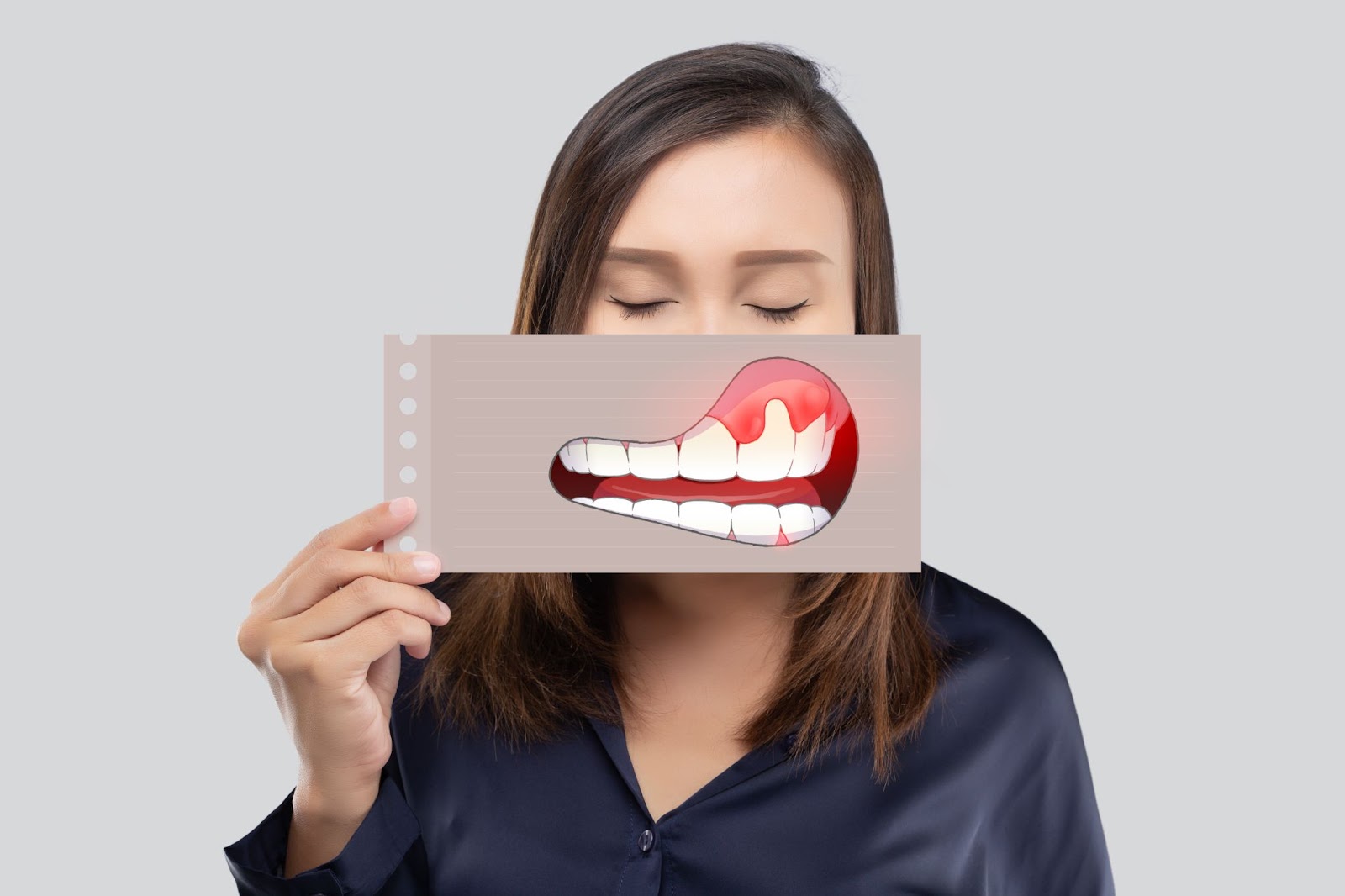 a woman is holding a visual of inflamed and irritated gums.