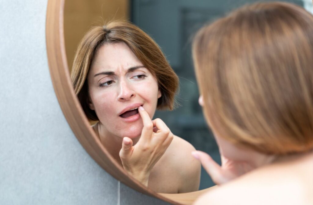 A patient looks into the mirror to check their gums for signs of recession.