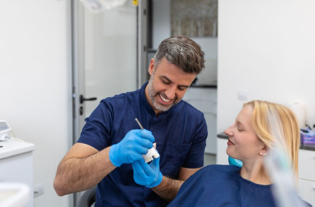 A dentist shows their patient how a dental bridge will mount in their mouth.