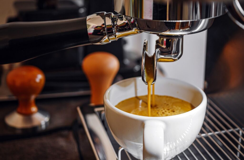 A close-up of espresso pouring into a white cup from a coffee machine.