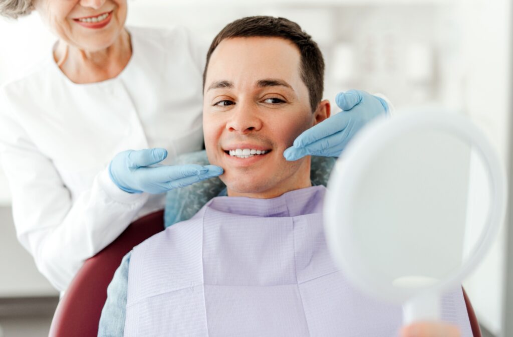 A patient smiles as their dentist unveils the results of their GBT dental cleaning.